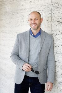 Mike Lind, a real estate professional known for a client-first, anti-hustle approach, leaning against a wall.