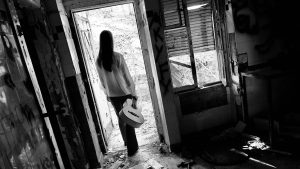Person walking out of an abandoned, decaying house — symbolizing an unsold home